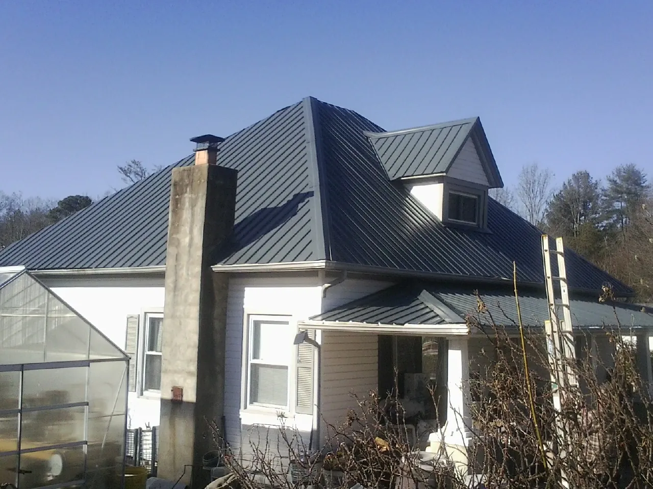 Dark blue standing seam metal roof on a white farmhouse with dormer — Slate & Tile Roof Repair by Roofing Brothers in Arvonia