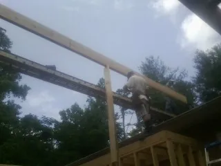 Carpenter setting a ridge beam over a new addition frame — Ice Dam Removal by Roofing Brothers in Arvonia
