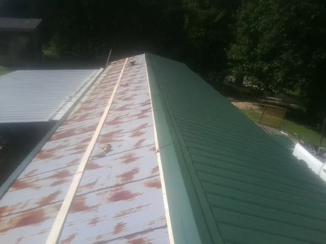 Old rusted panels beside newly installed green metal roofing — Wind Damage Roof Repair by Roofing Brothers in Arvonia