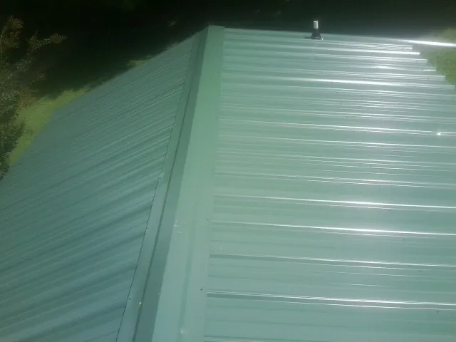 New green metal panels meeting at the ridge of a roof — Flat Roof Repair work by our crew in Arvonia