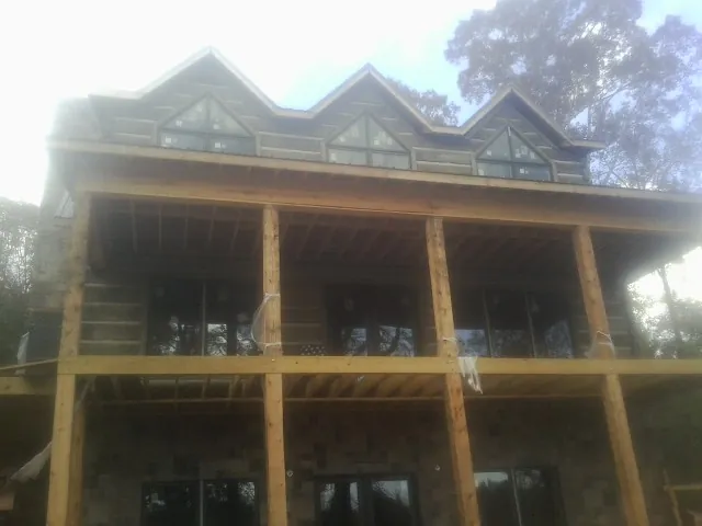 Dormers and porch framing on a large log home under construction — Roof Coating work by our crew in Arvonia