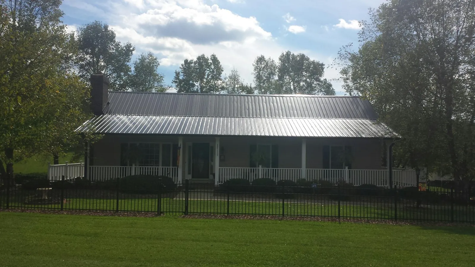 Gray metal roof on a brick ranch with a full width front porch — Gutter Guard Installation work by our crew in Arvonia
