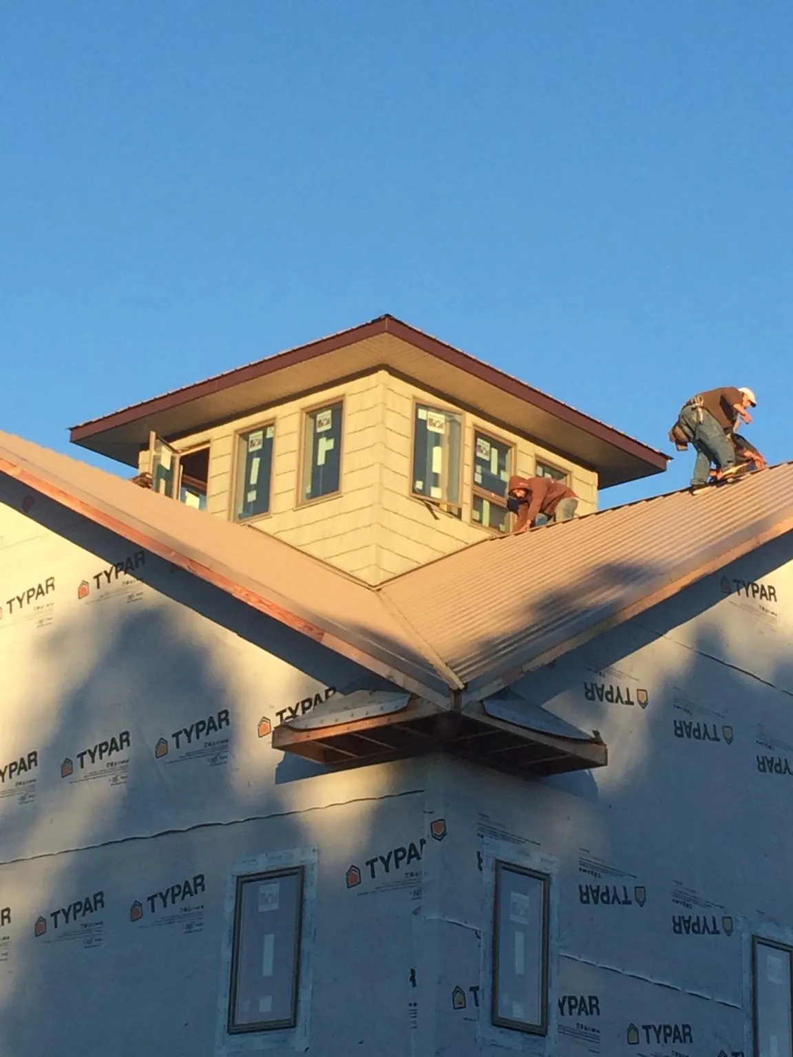 Roofers working around a rooftop cupola on a new metal roof at sunset — Roof Waterproofing in Arvonia by Roofing Brothers
